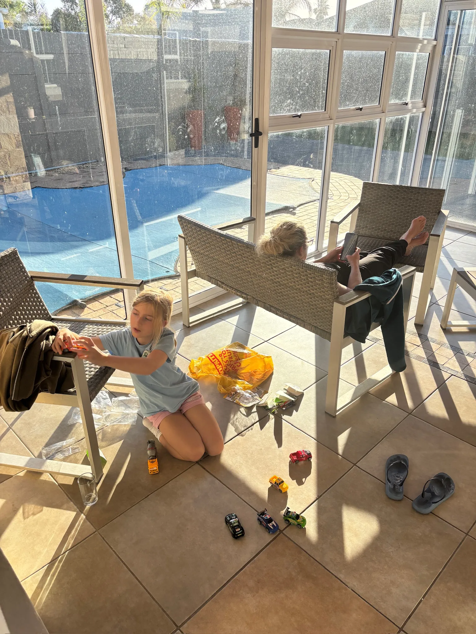 Merle spielt auf der Terrasse, dahinter der Pool